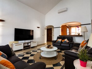 A modern living room with a flat-screen TV, leather sofas, a coffee table, and a potted plant. - Stunning detached villa with sea view, beautiful landscaped gardens,  A/C & wifi (PLAYA BLANCA)