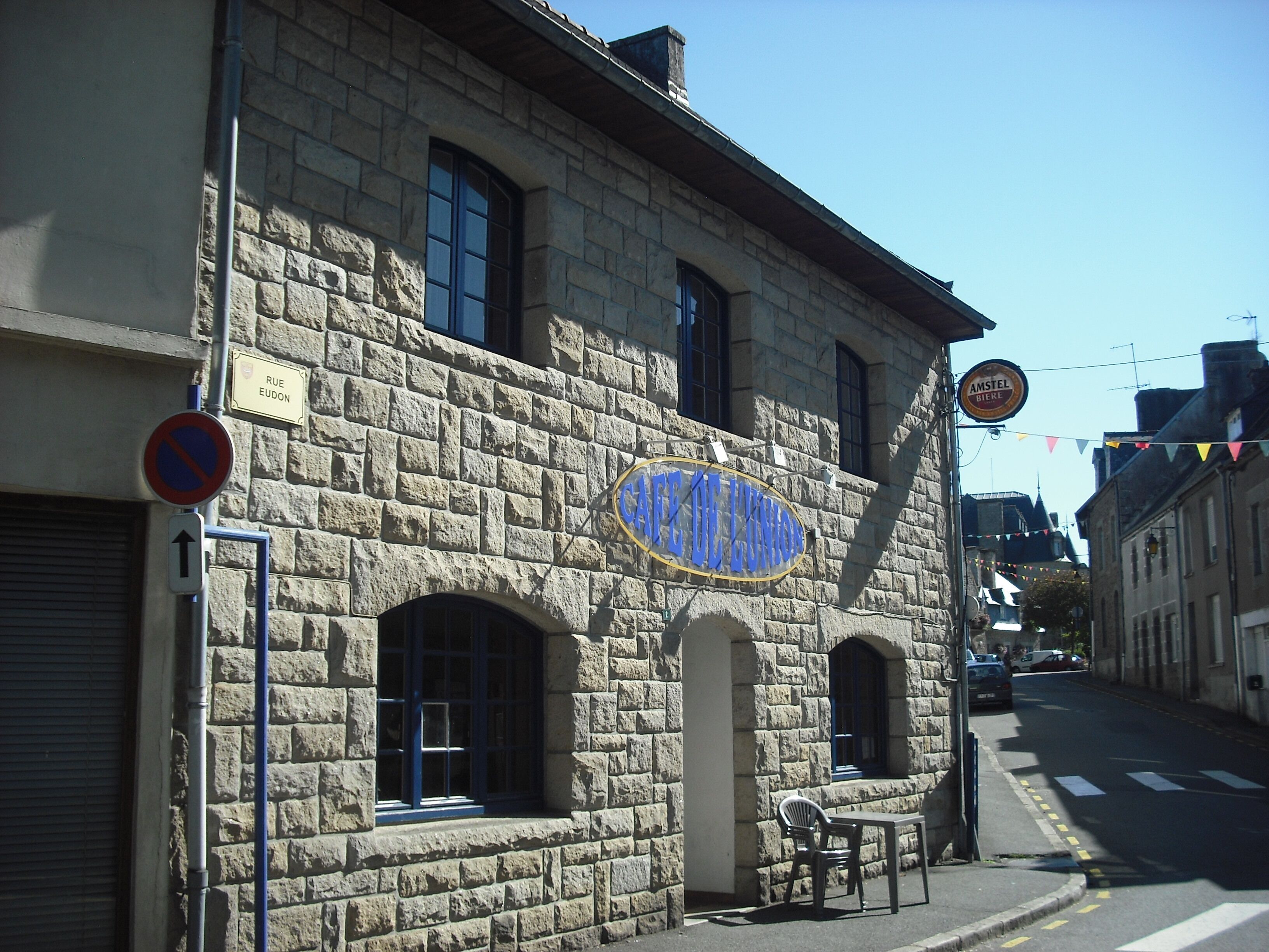 A stone building with a sign for "Cafe Olympos" and a no parking sign.
