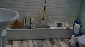 Una habitación pequeña y cerrada con tragaluces, un modelo de velero y decoración náutica.