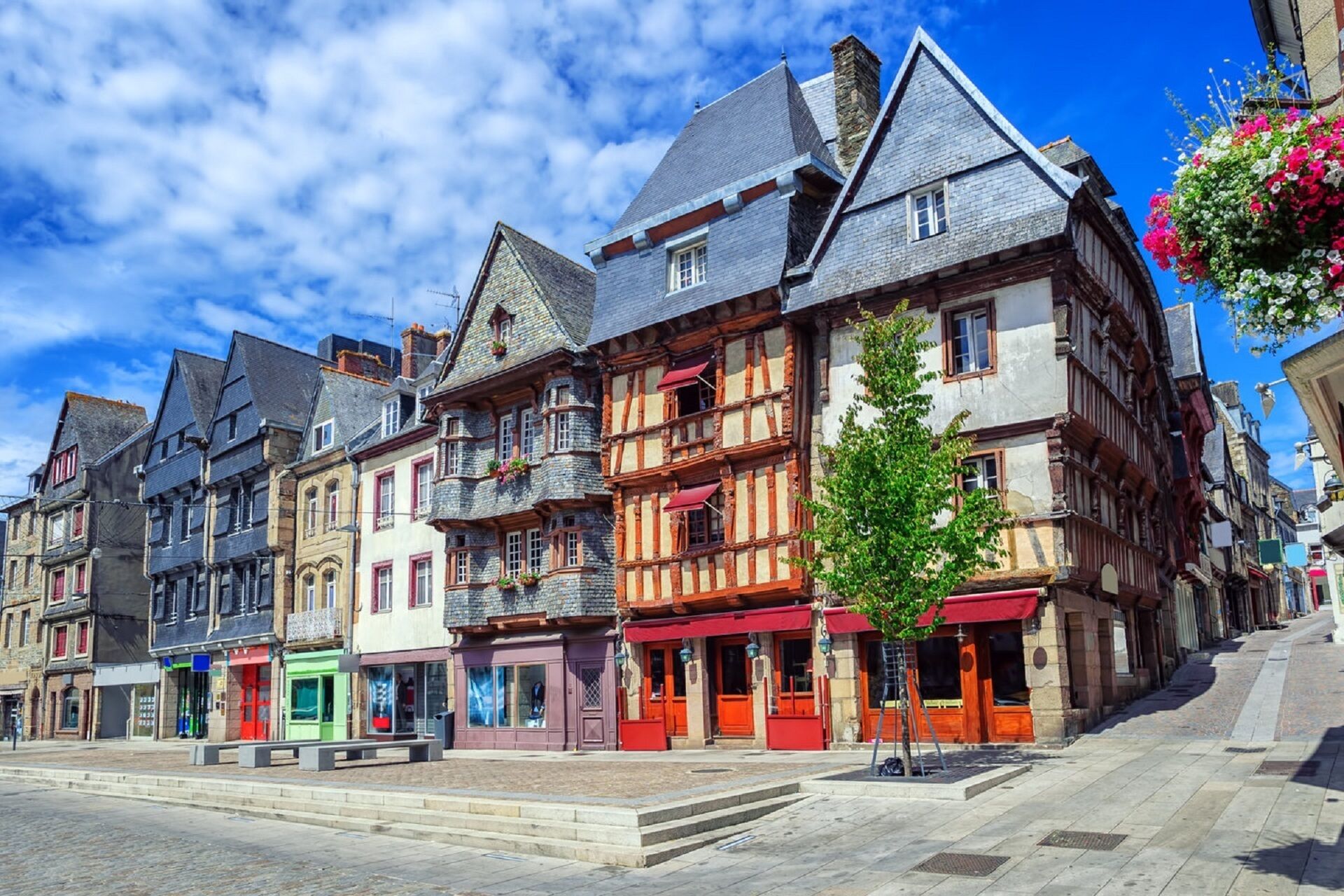 Een rij traditionele Europese gebouwen met vakwerk, een geplaveid straatje en een helderblauwe lucht.