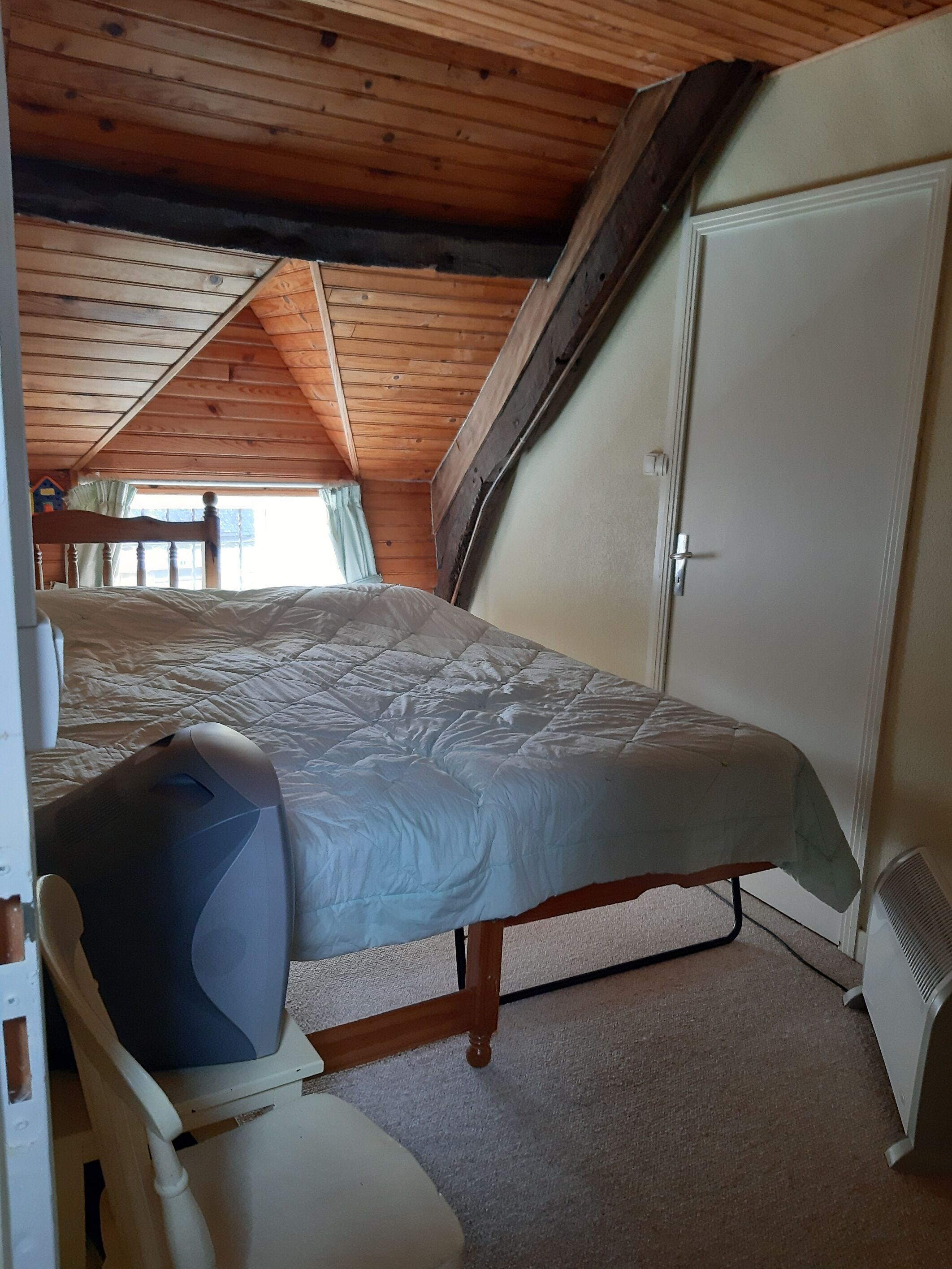 Een slaapkamer met een bed, stoel, kledingkast en raam.