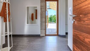 Un couloir moderne avec un mur d’accent en pierre, une porte en bois et une vue sur un jardin.