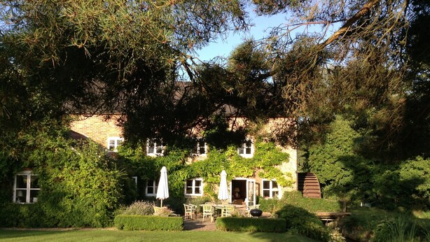 A traditional brick house with a well-maintained garden, a small pond, and outdoor seating.