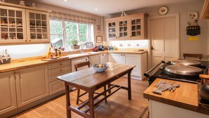 A kitchen with wooden cabinets, a wooden table, and a stove.