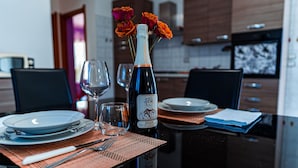 A dining table set with plates, cutlery, a wine bottle, and glasses, with a vase of flowers in the center.