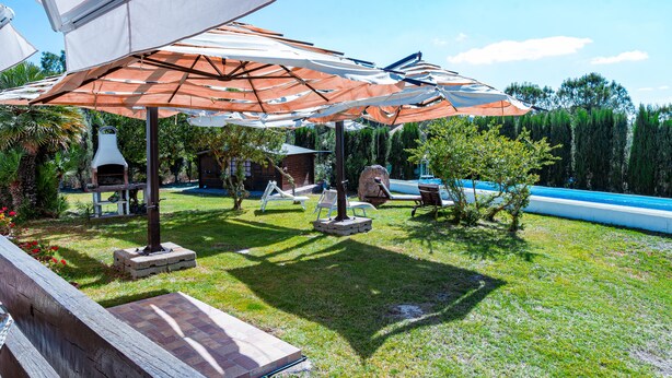A patio area with outdoor furniture, umbrellas, and a swimming pool.