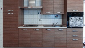 A modern kitchen with wooden cabinets, a stainless steel range hood, a gas stove, a sink, and a black oven.