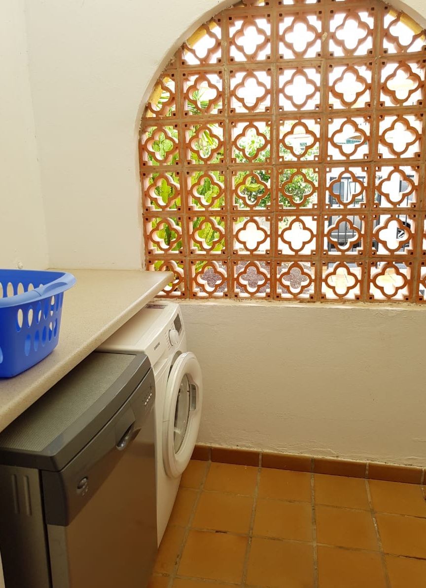 Un espace buanderie comprenant un lave-linge, un sèche-linge et un panier bleu posé sur un plan de travail.