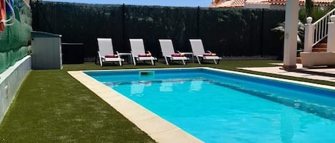 Una piscina al aire libre, una piscina climatizada, tumbonas