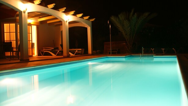 Una piscina amb zona de seients coberta i gandules.