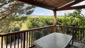 A covered outdoor area with a table and chairs, wooden railings, and a view of greenery and distant buildings. - La Magnanerie - Fantastic views, perfect base for the Ardeche and Chazzezac (Lablachère)