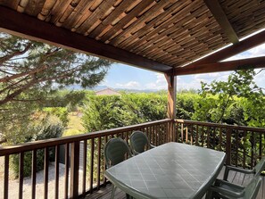 A covered outdoor area with a table and chairs, wooden railings, and a view of greenery and distant buildings. - La Magnanerie - Fantastic views, perfect base for the Ardeche and Chazzezac (Lablach ère)