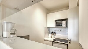 A modern kitchen with white cabinetry, a built-in microwave, and a coffee maker on the counter.