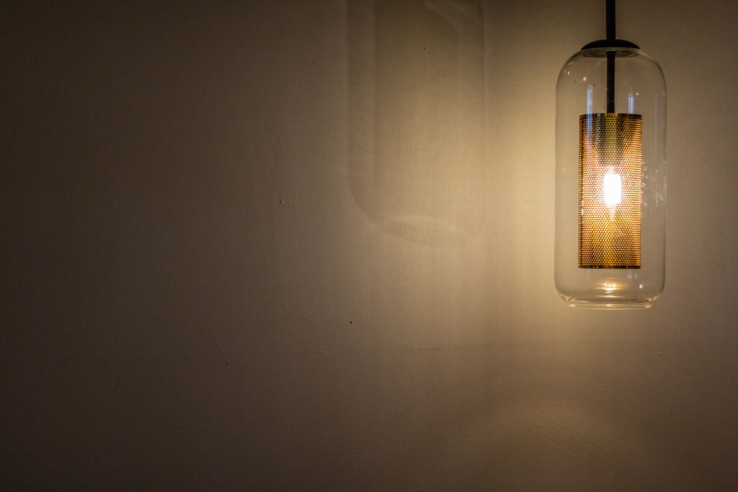 Una lampada a sospensione con paralume in vetro strutturato.
