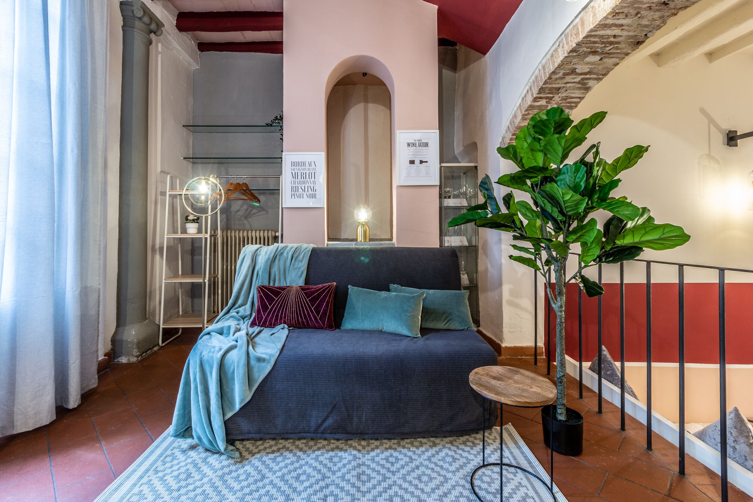 Una habitación acogedora con un sofá, una mesita redonda y una planta grande en maceta.
