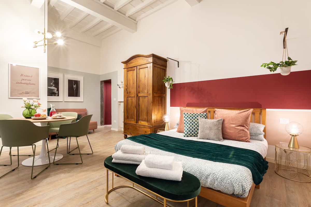 Een moderne slaapkamer met een houten garderobe, een zithoek met een tafel en stoelen, en een bank met handdoeken.