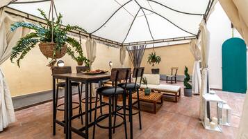 Un área de comedor con carpas, una mesa, sillas y plantas colgantes.