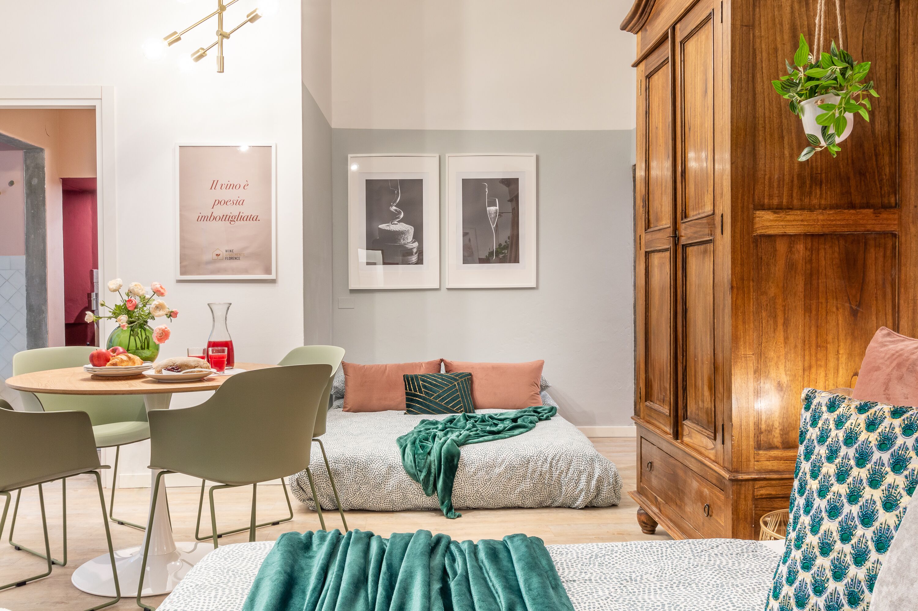 A modern living room with a bed, a dining area with a table and chairs, and a wooden cabinet.