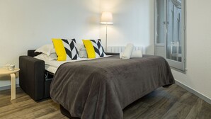 Een moderne slaapkamer met een bed, nachtkastje, lamp en een raam.
