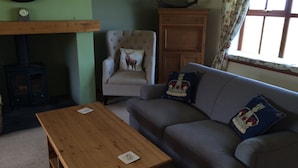 A cozy living room with a sofa, a wooden coffee table, a fireplace, and a decorative deer head. - In the heart of the Highlands located on a Private Sporting Estate (Lairg)