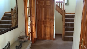 A hallway with a wooden door, a staircase, and a console table with decorative items. - In the heart of the Highlands located on a Private Sporting Estate (Lairg)