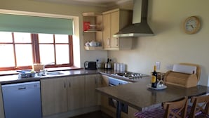 A kitchen with a dishwasher, stove, and a dining area with chairs. - In the heart of the Highlands located on a Private Sporting Estate (Lairg)