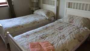 A twin bedroom with two beds, each with a floral quilt and a nightstand with a lamp. - In the heart of the Highlands located on a Private Sporting Estate (Lairg)