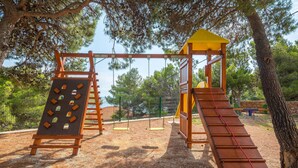 A playground with a wooden climbing structure, a slide, and swings.