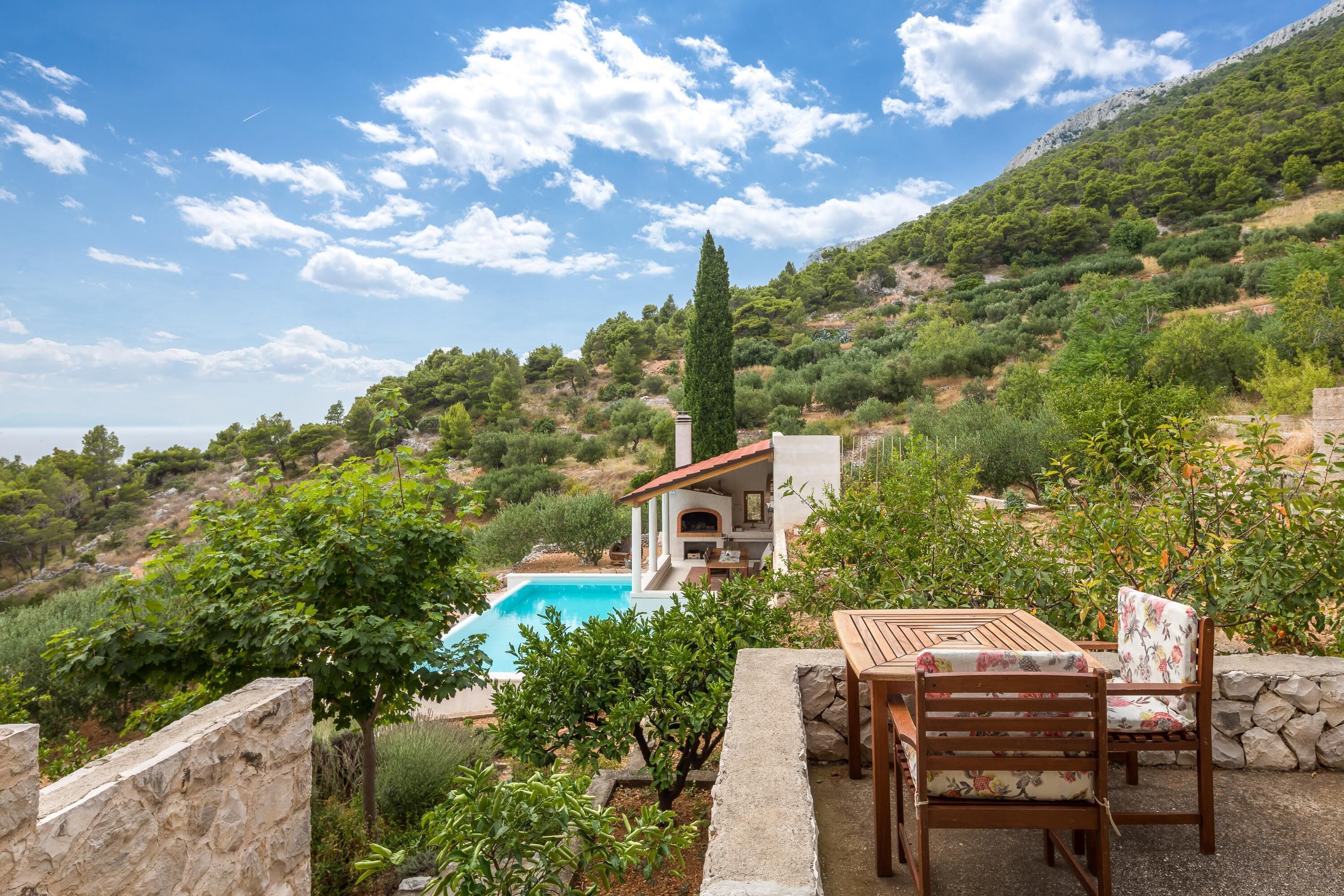 Una villa con piscina, mobiliario exterior y vistas a las colinas circundantes.