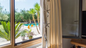 A room with a large window overlooking a pool and greenery. - PREMIUM: GRAND AND ELEGANT VILLA (Sa pobla)