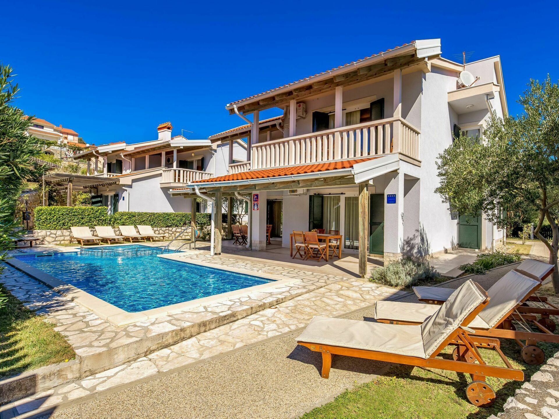 A two-story building with a swimming pool, outdoor seating, and a covered patio area.