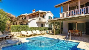 A swimming pool with lounge chairs and a dining area, surrounded by a white building with balconies. - Lovely apartment for 4 guests with WIFI, A/C, pool, TV and terrace (Senj)