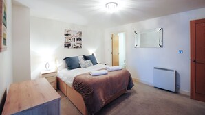Ein Schlafzimmer mit einem Bett, Nachttischen, einem Heizkörper und einer Tür.