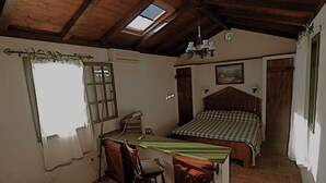 A bedroom with a wooden ceiling, a skylight, a bed with a checkered bedspread, a desk with a chair, and a small window with curtains. - Cozy Pet-Friendly 1BR Apartment for 3 (Veli Lošinj)