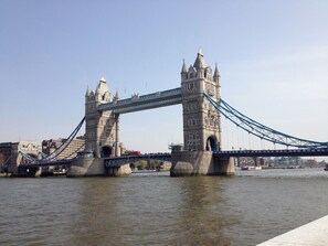 A large stone bridge with two towers and a blue suspension cable.