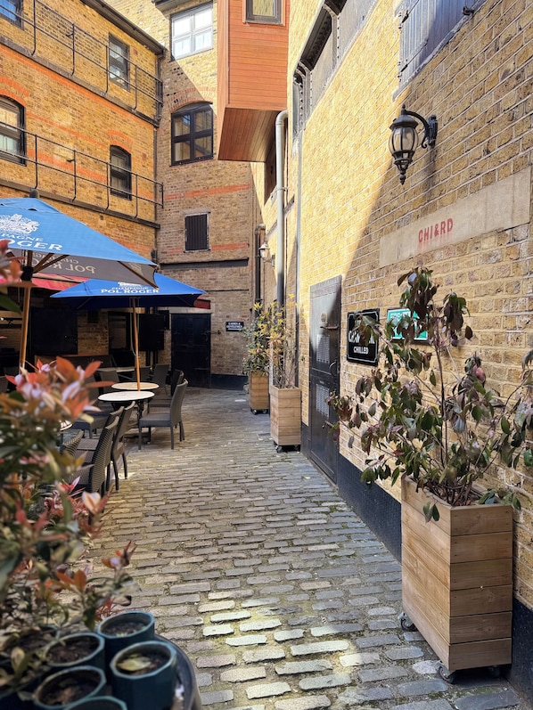 A cobblestone alley with outdoor seating, a wooden planter, and a sign reading "CHI&RD".