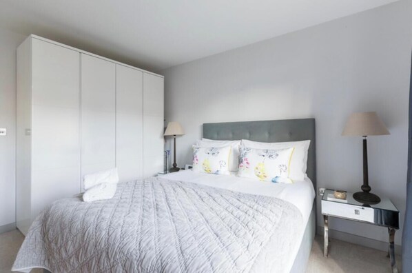 A bedroom with a bed, nightstands, a lamp, and a wardrobe.
