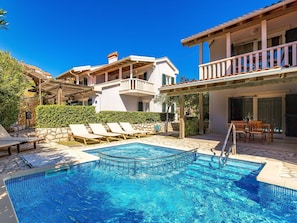 Zona de piscina con sillones de descanso y una terraza de madera.