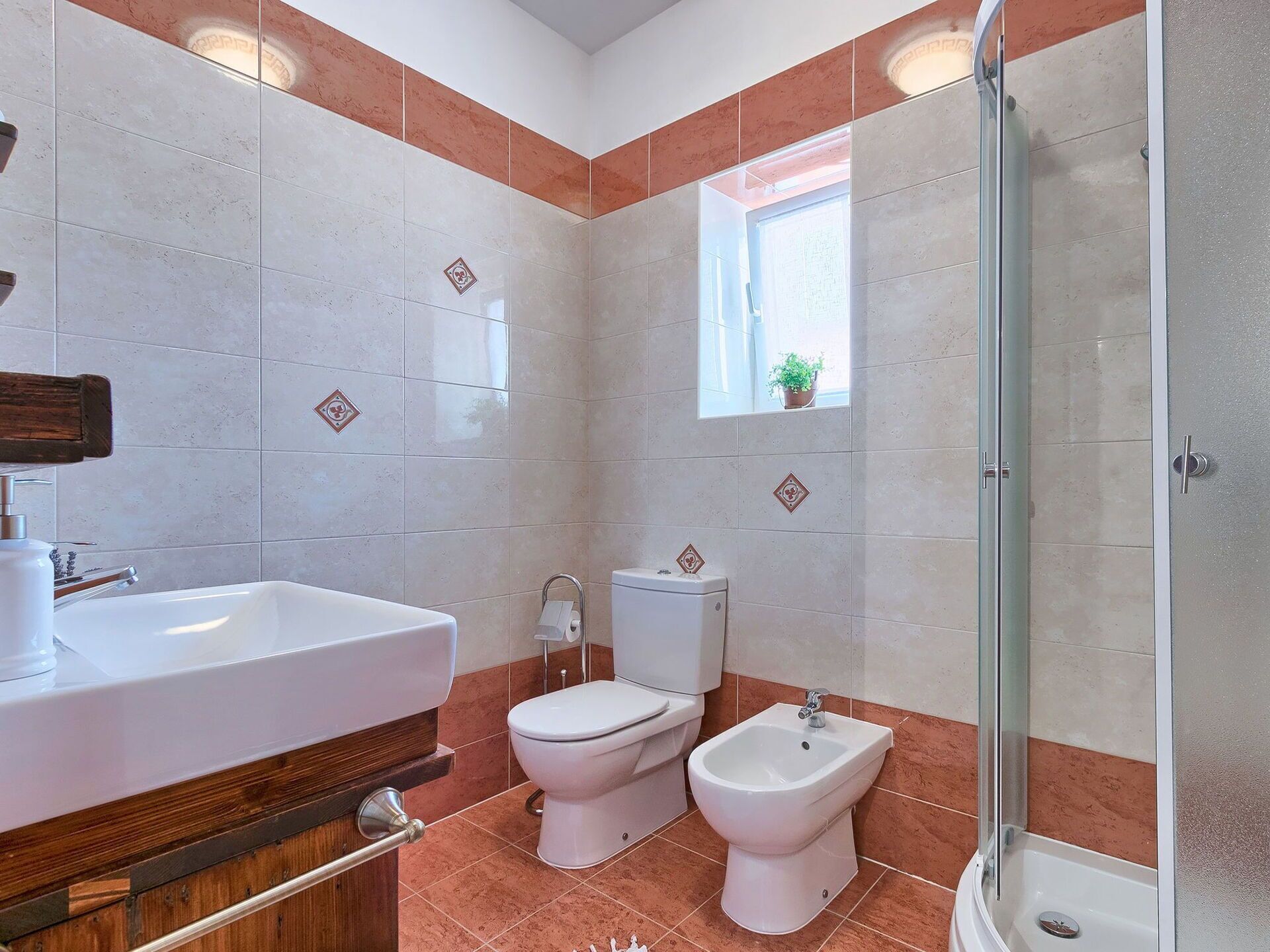 A bathroom with a sink, toilet, bidet, and shower.