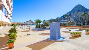 Une cour d’hôtel avec une piscine, des palmiers et une montagne en arrière-plan.