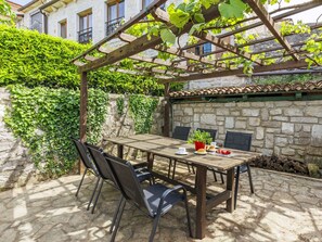 An outdoor patio with a wooden table and chairs, surrounded by stone walls and greenery. - Stunning  villa for 6 guests with WIFI, A/C, TV and pets allowed (Vrsar)