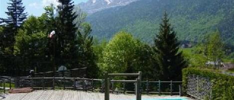 Zona de piscina con vistas a montañas y árboles.