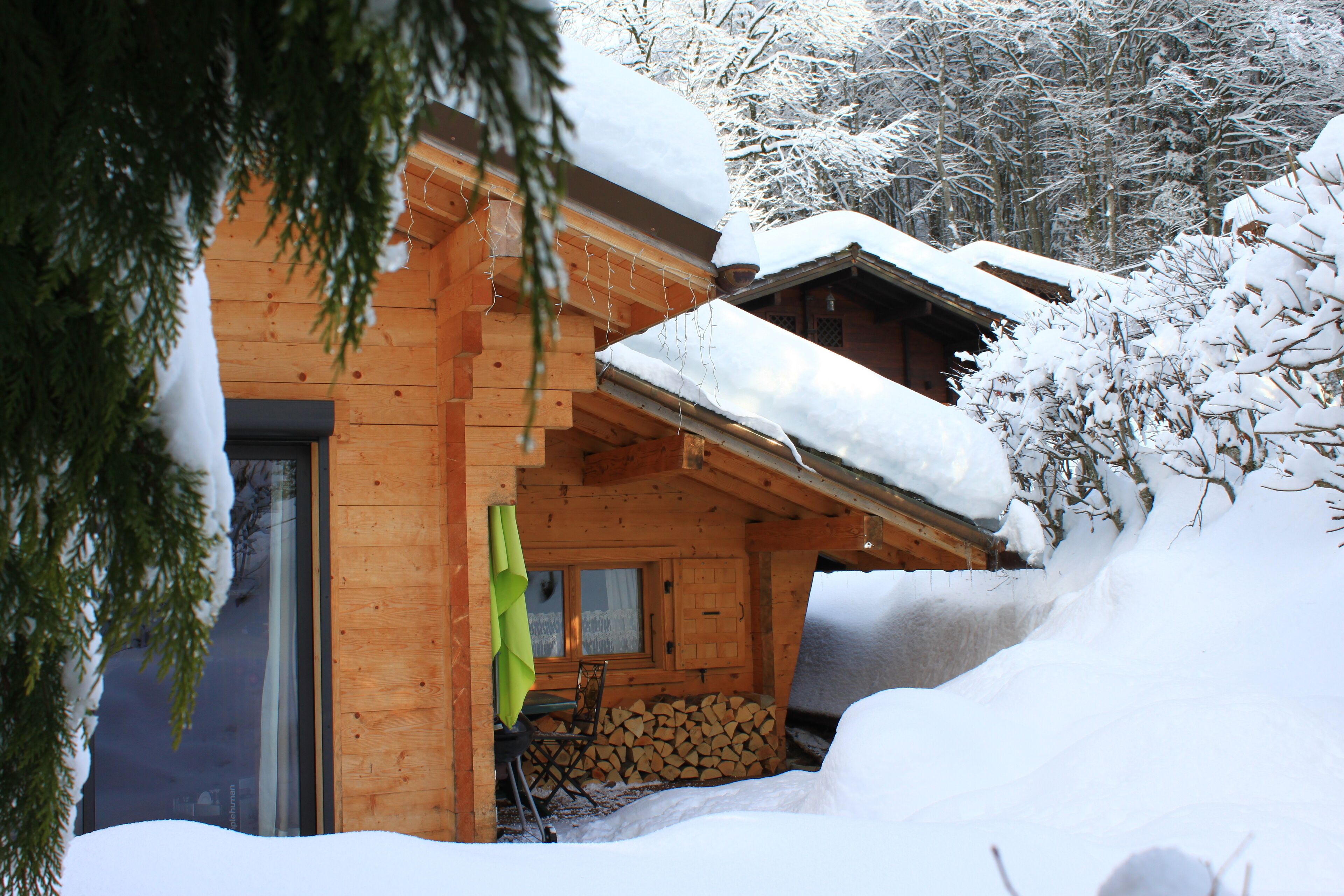 Une cabane en bois avec un toit enneigé, une porte en verre et une fenêtre.
