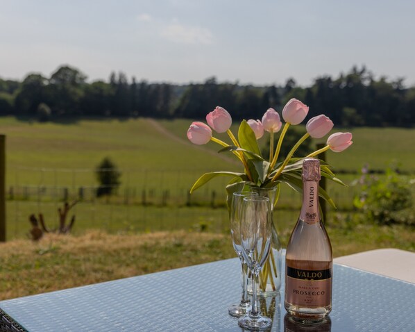 A table with a bottle of Valdo Prosecco and a vase of pink tulips. - Holly Cottage - Tranquil luxury country cottage in the Surrey Hills (Ewhurst)