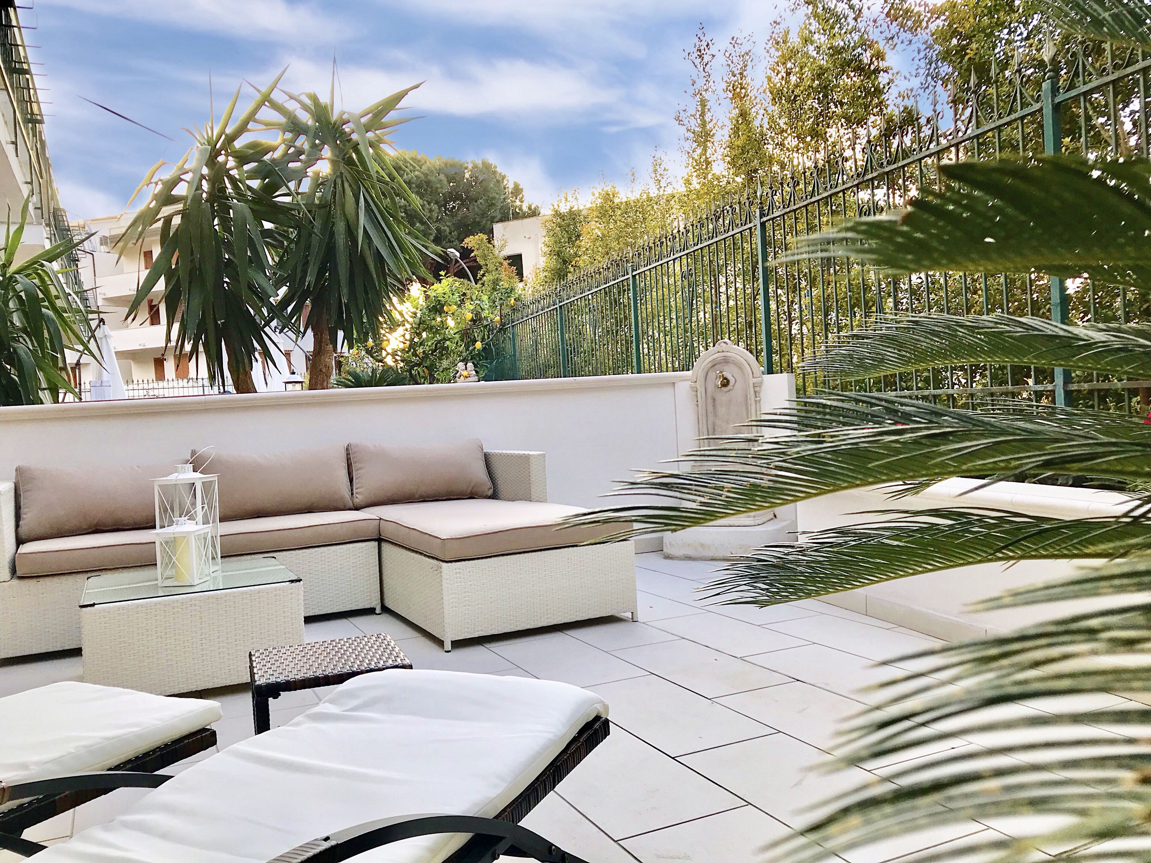 A rooftop terrace with a sectional sofa, lounge chairs, and a decorative lantern.