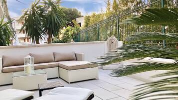 A rooftop terrace with a sectional sofa, lounge chairs, and a decorative lantern.