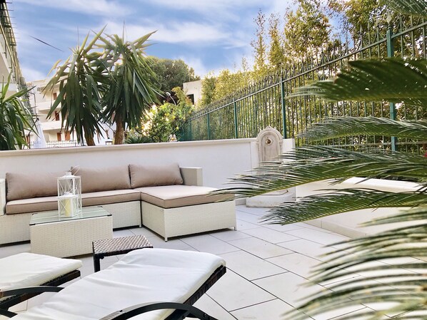 A rooftop terrace with a sectional sofa, lounge chairs, and a decorative lantern.