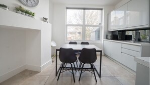 Eine moderne Küche mit Esstisch, zwei Stühlen, einer Uhr und einem Fenster.