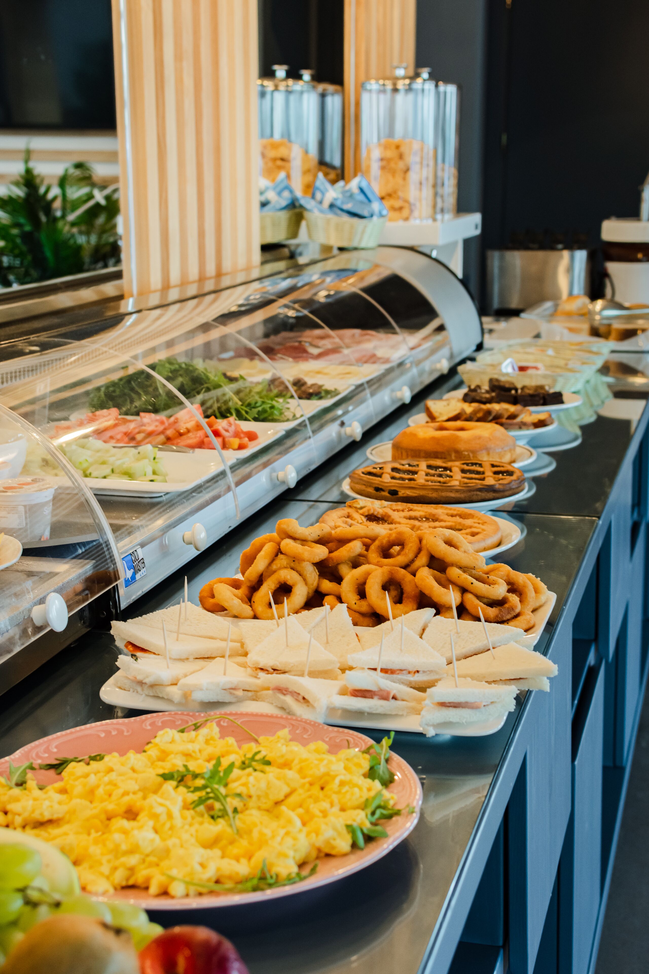 Un bufé con diversas opciones de comida, incluyendo sándwiches, gofres y ensaladas.