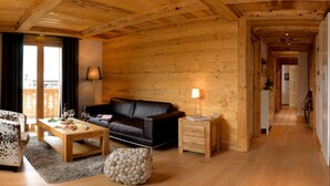 En mysig interiör i en stuga byggd av timmer, med en soffa klädd i läder, ett bord i trä som används som soffbord och ett litet sidobord med en lampa.